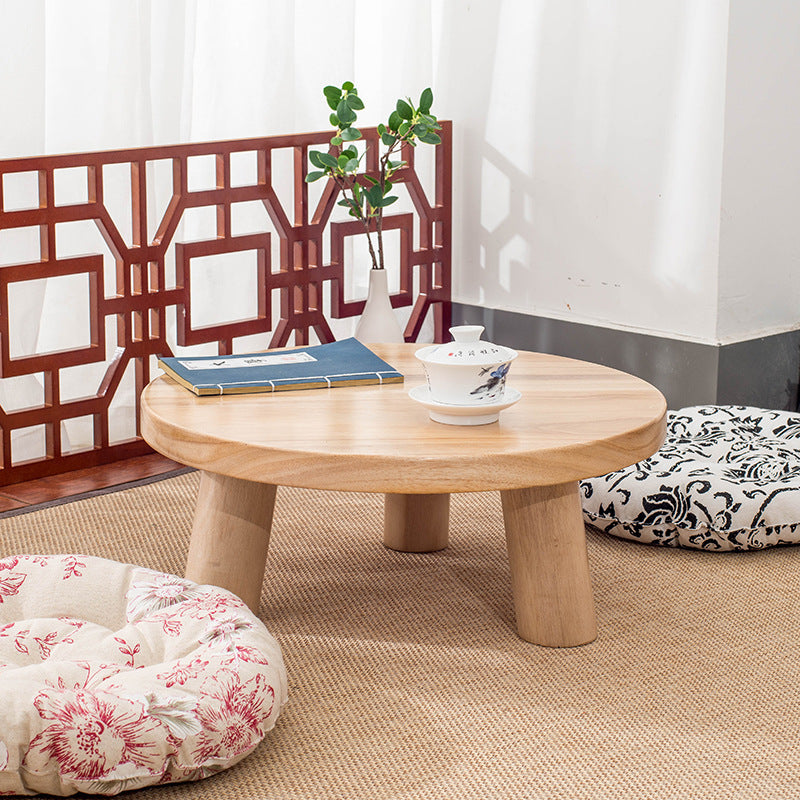Natural Round Timber Coffee Table with a book and tea set in a room with floral cushions and a decorative screen.