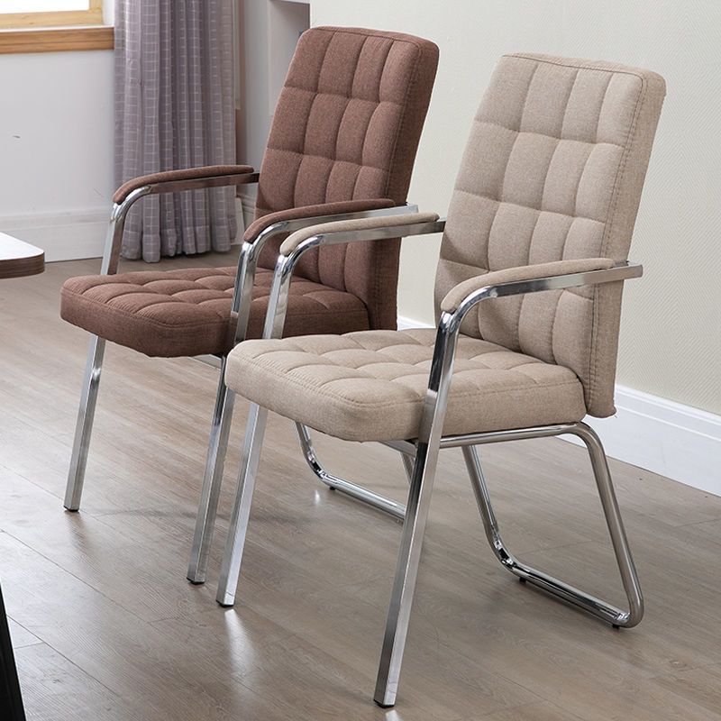 Two modern armchairs with tufted upholstery and chrome metal frames, shown in a room setting. One chair is upholstered in a warm brown fabric, and the other in a light beige fabric.