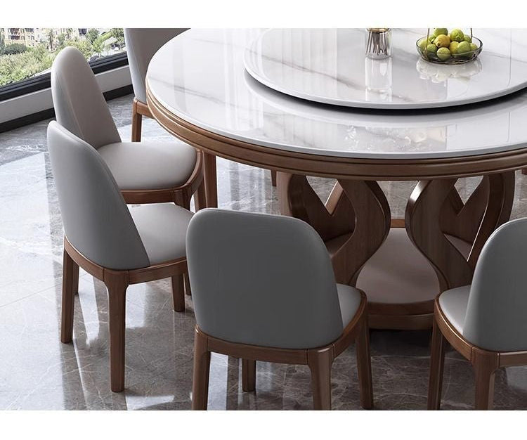 A dining table set with gray upholstered chairs and a round white marble tabletop