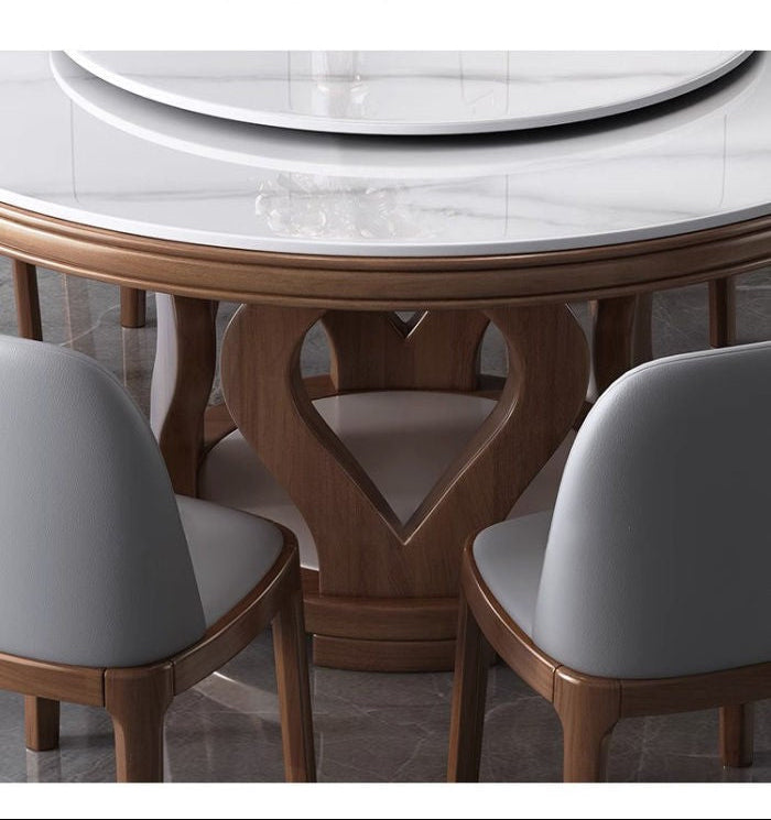 Round dining table with a white marble-look top and a heart-shaped wooden frame base, surrounded by gray upholstered chairs. 