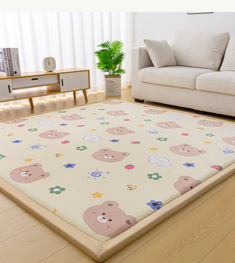 A beige baby play mat with a cute cartoon bear pattern, styled on a light wood floor in a bright, modern living room next to a cream sofa.