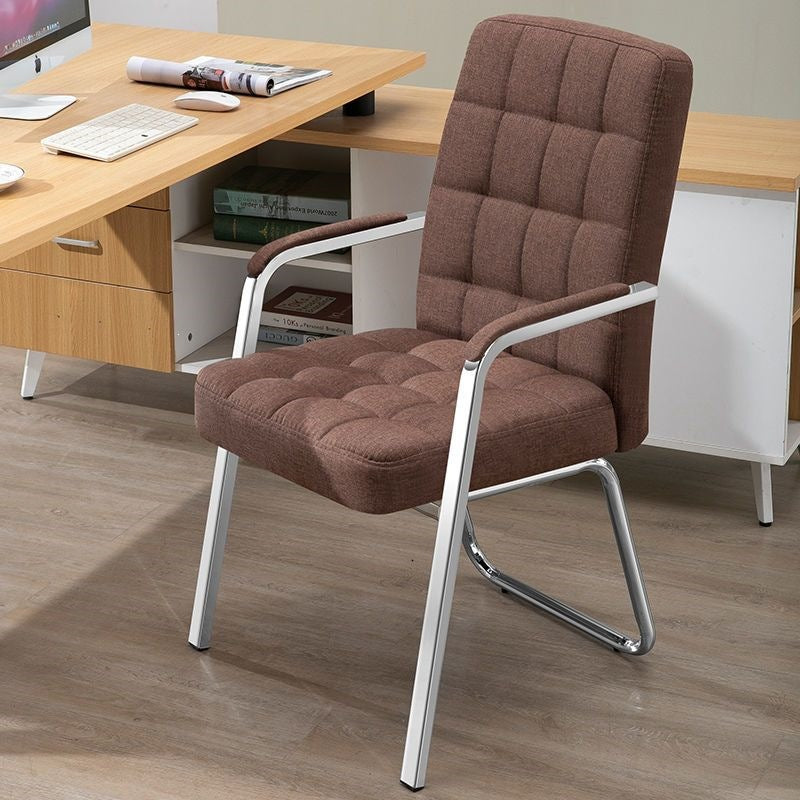 A brown tufted fabric office chair with a silver metal frame, positioned in front of a wooden desk in a home office setting.