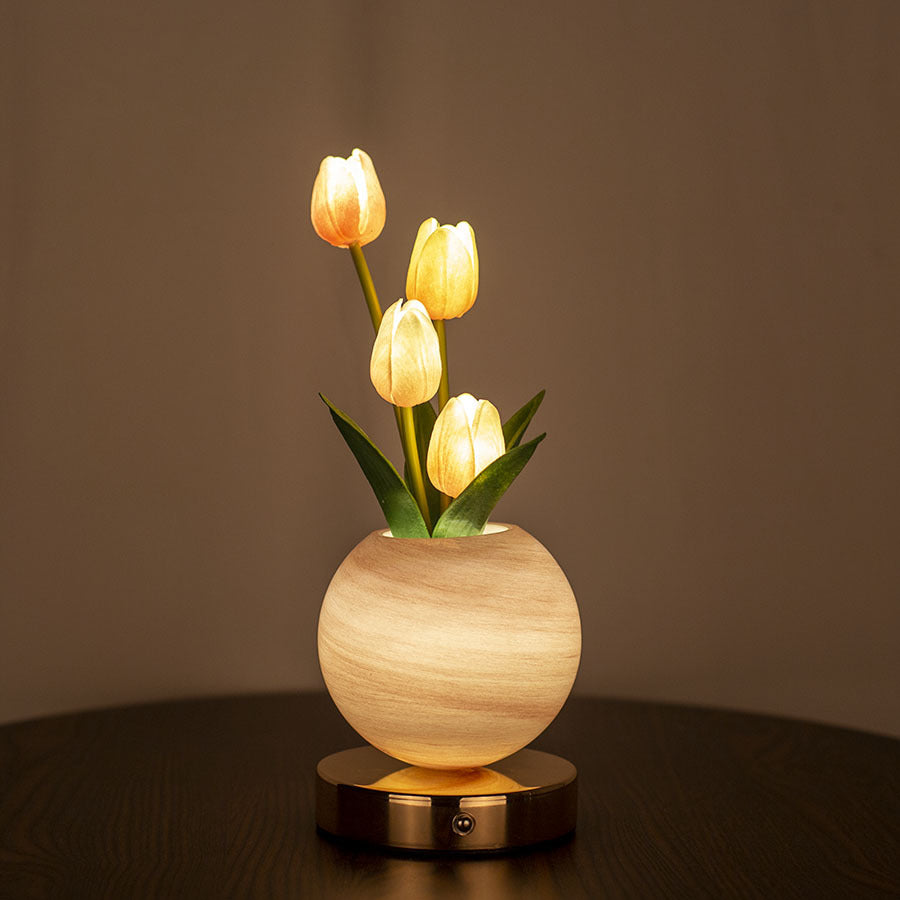 Decorative lamp with glowing tulips in a wooden vase on a dark surface.