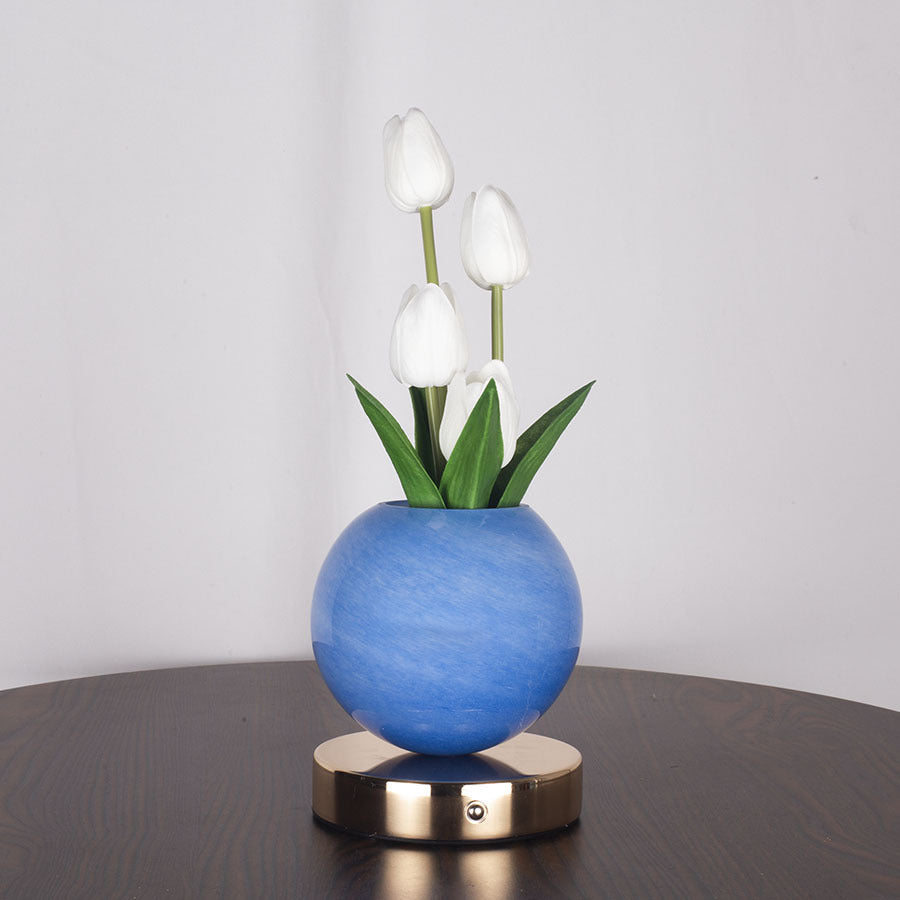 Blue spherical vase with white tulips on a wooden surface