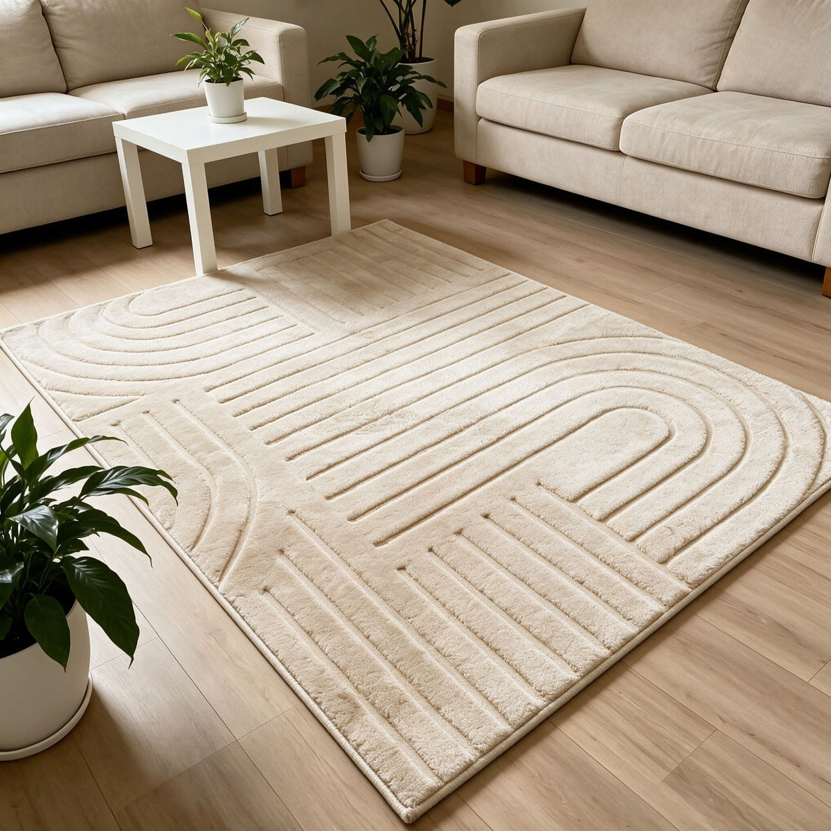 A large cream-colored area rug with a modern geometric wavy pattern, shown on a light wood floor in a bright, modern living room setting.