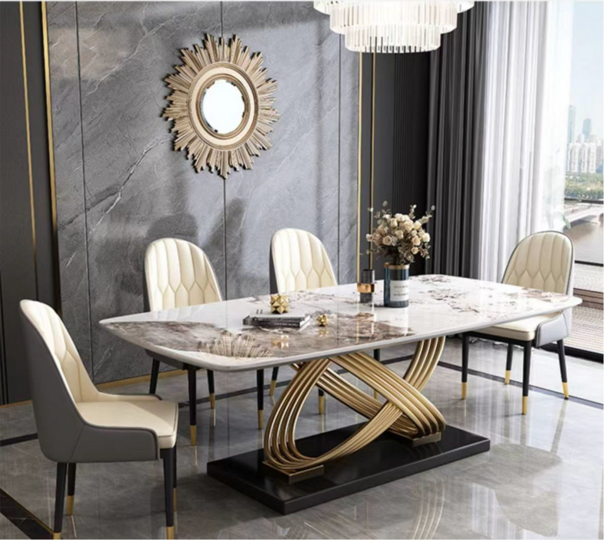 A luxury modern dining room set featuring a rectangular marble-top dining table with a twisted gold metal base, surrounded by four cream tufted chairs with black legs. The room has a dark gray marble accent wall with a gold sunburst mirror and gold trim.